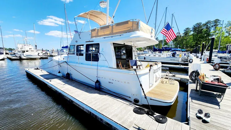 Slide: The Image of 2015 Beneteau Swift Trawler 34 docked at marina, sunny day, American flag displayed. - 5