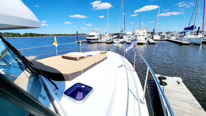 Slide: The Image of 2015 Beneteau Swift Trawler 34 docked at marina, clear blue sky, calm water. - 6
