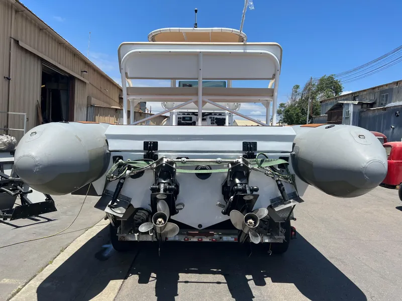 Slide: The Image of 1995 Nautica 33 Commercial RIB with dual outboard motors, docked in an industrial area. - 11