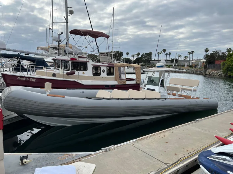 Slide: The Image of 1995 Nautica 33 Commercial RIB docked at marina, overcast sky, adjacent boats visible. - 9