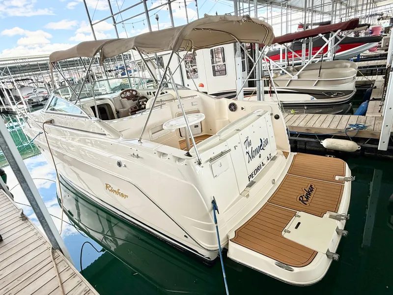Slide: The Image of 2006 Rinker 270 Express Cruiser docked in marina, featuring beige canopy and spacious deck. - 0