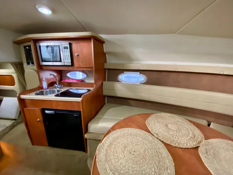 Slide: The Image of 2006 Rinker 270 Express Cruiser interior with kitchenette, seating, and dining area. - 11