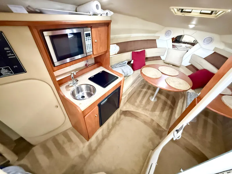 Slide: The Image of 2006 Rinker 270 Express Cruiser interior with kitchenette, seating area, and modern amenities. - 12