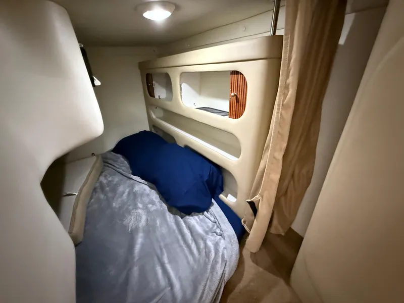 Slide: The Image of 2006 Rinker 270 Express Cruiser cabin interior with cozy bedding and ambient lighting. - 15