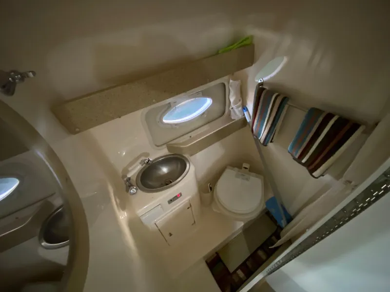 Slide: The Image of 2006 Rinker 270 Express Cruiser bathroom with sink, toilet, and porthole window. - 17