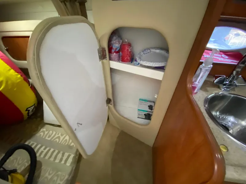 Slide: The Image of 2006 Rinker 270 Express Cruiser interior with open cabinet, sink, and stored items. - 19