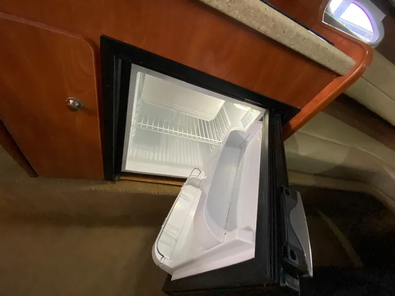 Slide: The Image of 2006 Rinker 270 Express Cruiser interior fridge with open door, showcasing storage space. - 22