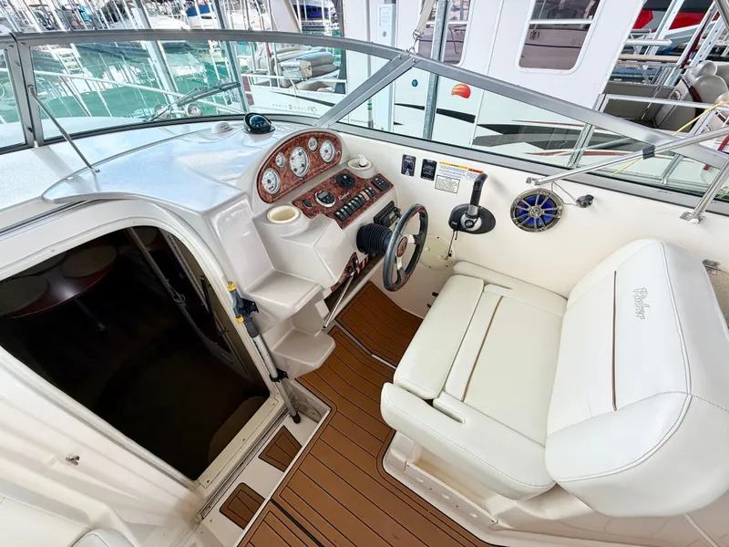 Slide: The Image of 2006 Rinker 270 Express Cruiser helm with white seating and wooden flooring. - 4