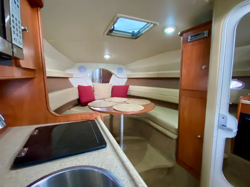 Slide: The Image of 2006 Rinker 270 Express Cruiser cabin with dining area, kitchenette, and skylight. - 9