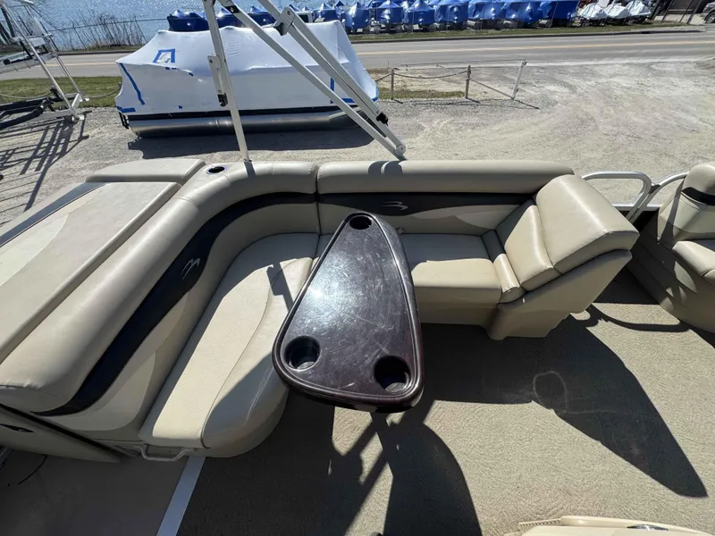 Slide: The Image of 2015 Bennington 20 SL pontoon boat interior with beige seating and a central table. - 9