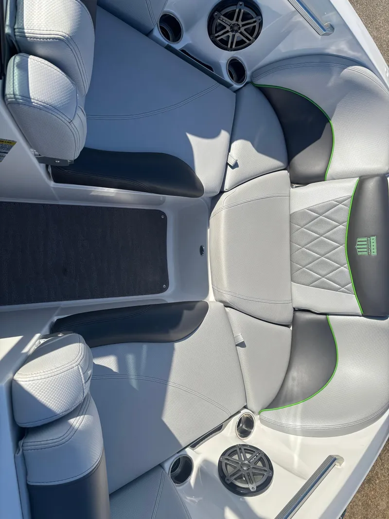 Slide: The Image of 2015 MasterCraft X23 boat interior with gray and black seating, green accents, and cup holders. - 17