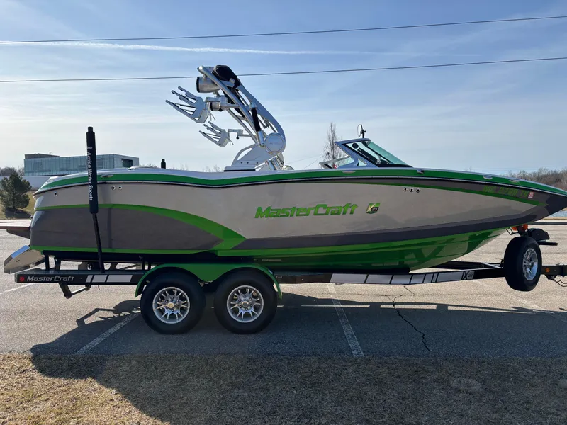 Slide: The Image of 2015 MasterCraft X23 boat on trailer, green and gray design, parked outdoors. - 20