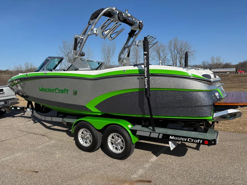 Slide: The Image of 2015 MasterCraft X23 boat with green accents on a trailer, parked outdoors. - 3
