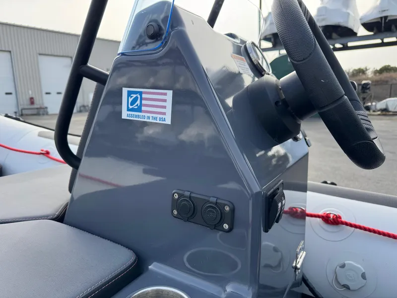 Slide: The Image of 2023 Zodiac Open 4.2 boat console with steering wheel, USA assembly sticker, and dual sockets. - 12