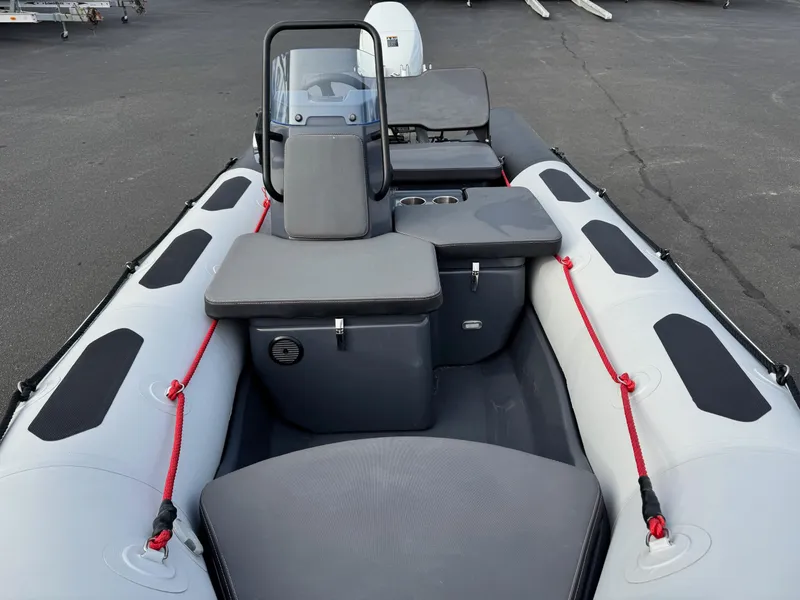 Slide: The Image of 2023 Zodiac Open 4.2 inflatable boat with seating and console, docked on asphalt surface. - 6