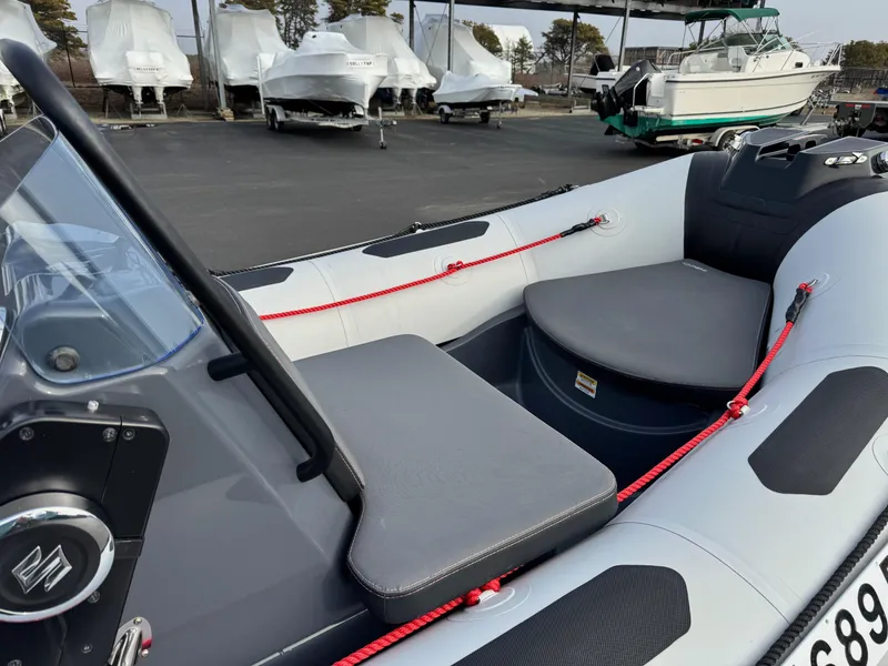 Slide: The Image of 2023 Zodiac Open 4.2 boat interior with seating and red ropes, parked in a marina. - 7