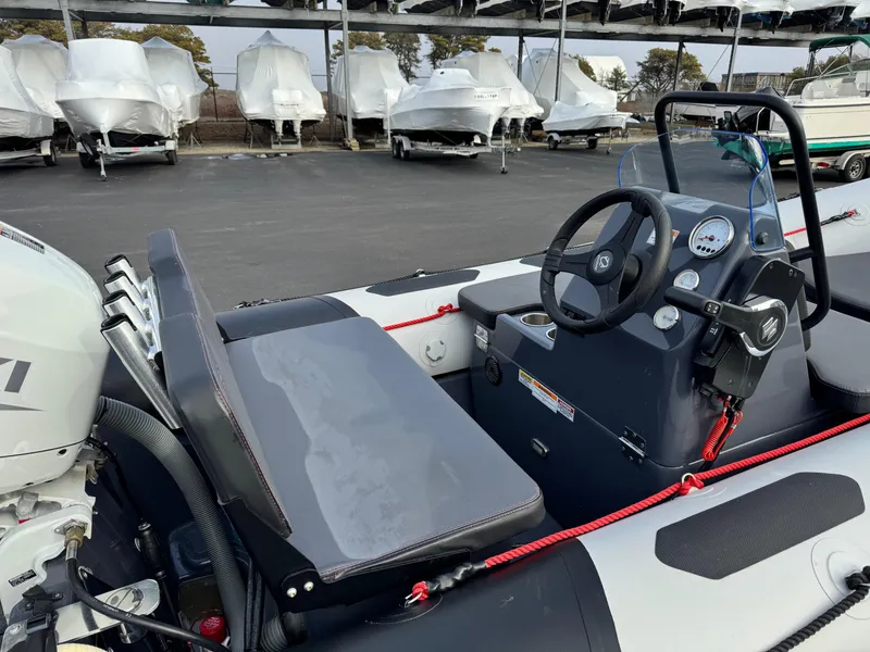 Slide: The Image of 2023 Zodiac Open 4.2 boat interior with steering wheel and seating, parked in marina. - 8