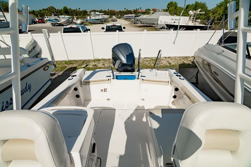 Slide: The Image of 2016 Everglades 230 Dual Console boat interior with seating and outboard motor in marina. - 15