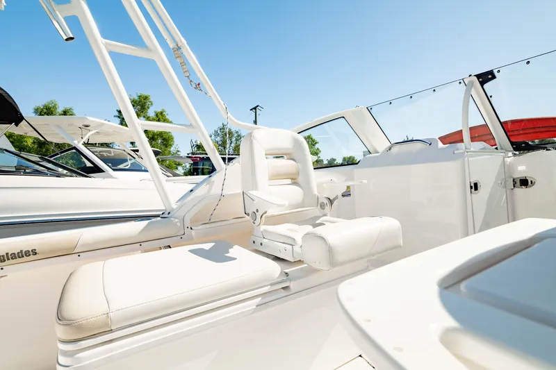 Slide: The Image of 2016 Everglades 230 Dual Console boat interior with white seating and clear blue sky. - 8