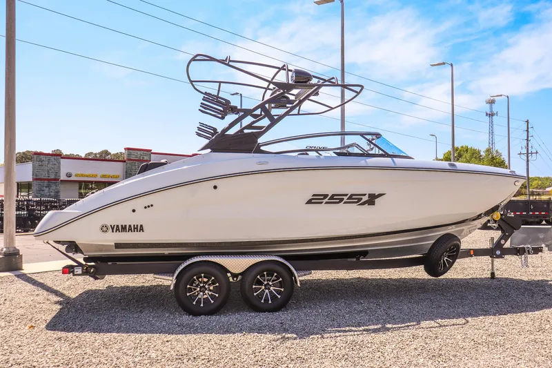 Slide: The Image of 2024 Yamaha Boats 255XD on trailer, sleek design, white exterior, parked outdoors. - 10