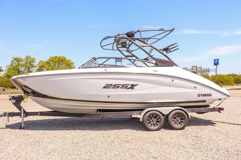 Slide: The Image of 2024 Yamaha Boats 255XD on trailer, sleek design, white exterior, parked outdoors. - 6