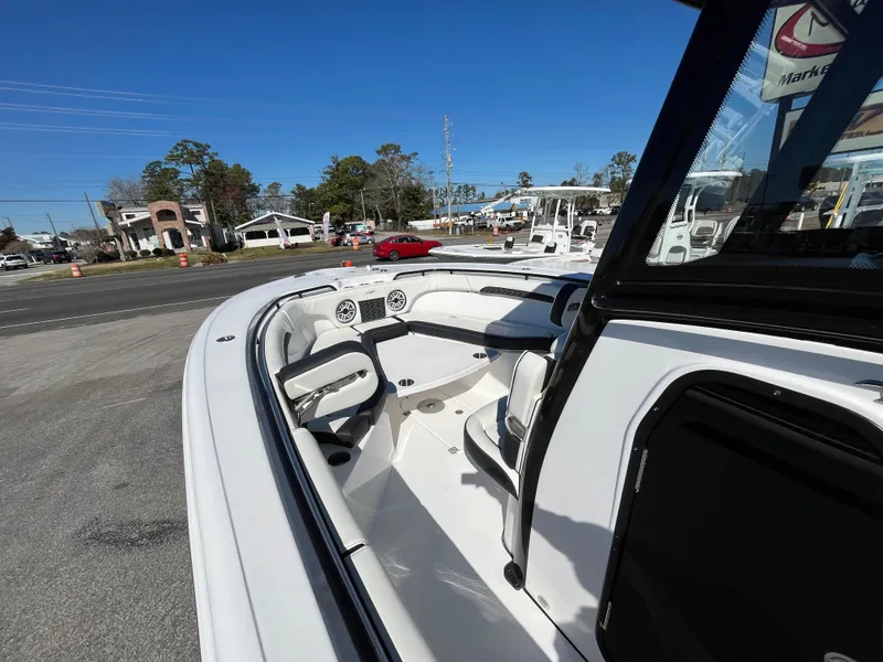 Slide: The Image of 2024 Tidewater 280 CC Adventure boat interior with seating and dashboard, parked outdoors. - 18