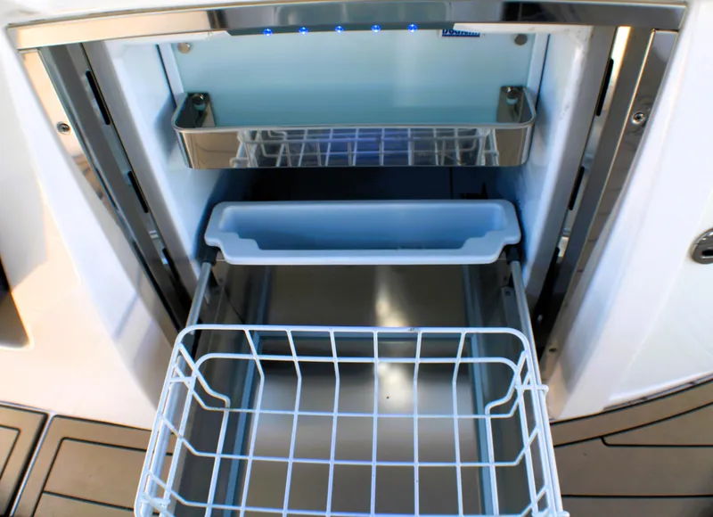 Slide: The Image of 2022 Regal 33 OBX boat refrigerator with open compartments and wire basket. - 19