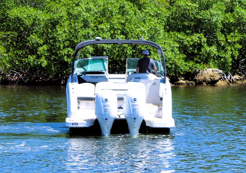 Slide: The Image of 2022 Regal 33 OBX boat cruising on a sunny day near lush greenery. - 5