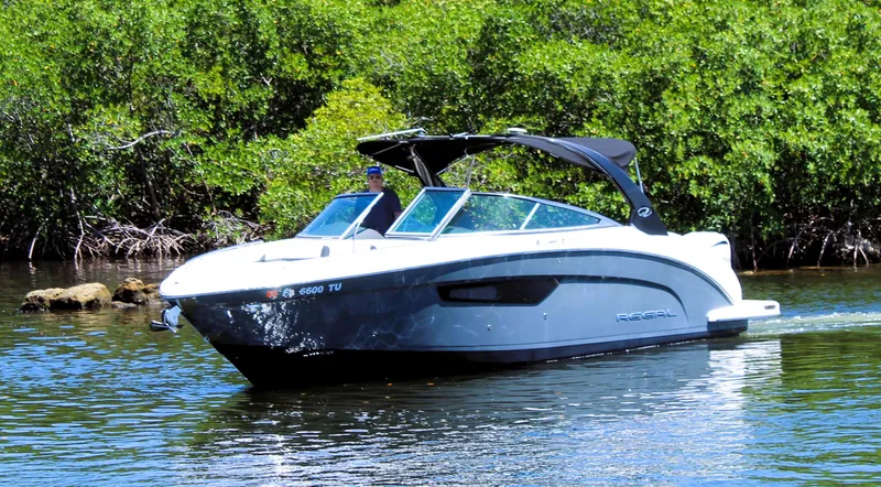Slide: The Image of 2022 Regal 33 OBX boat cruising on a calm river with lush greenery. - 7
