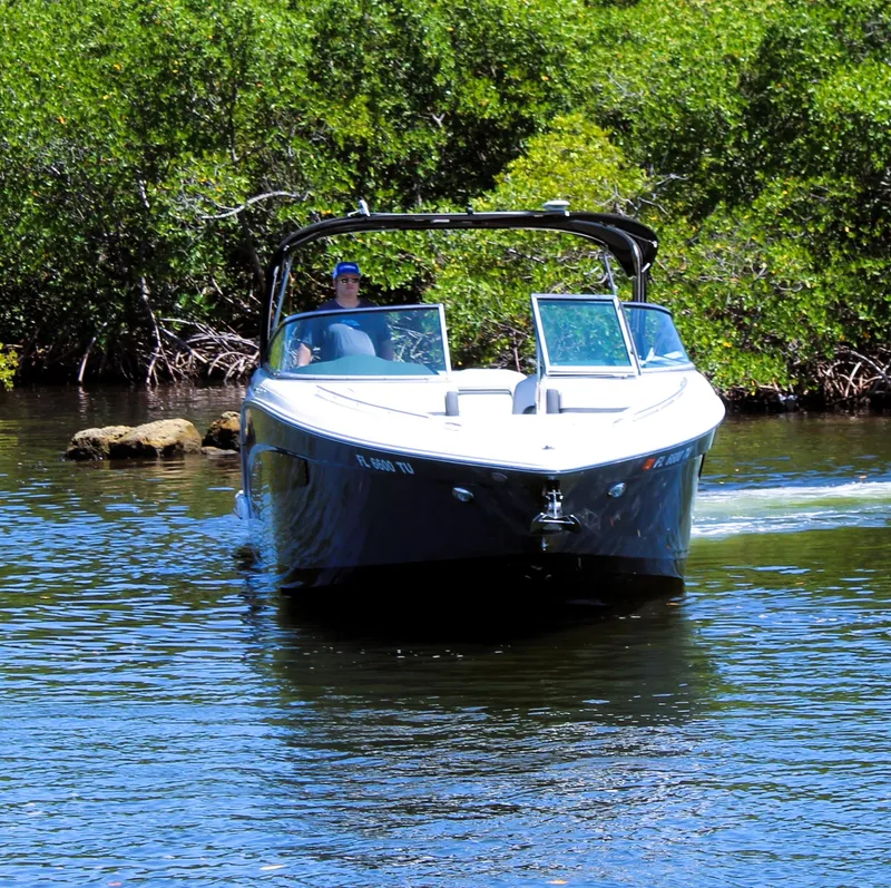 Slide: The Image of 2022 Regal 33 OBX boat cruising on a calm river with lush greenery. - 8