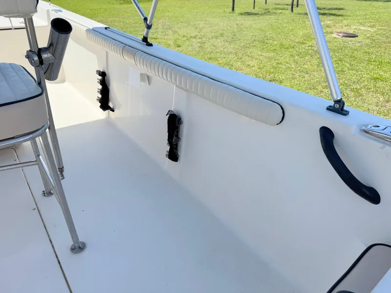 Slide: The Image of 2020 Carolina Skiff 19 LS interior with seating and rod holders, set against a grassy background. - 24