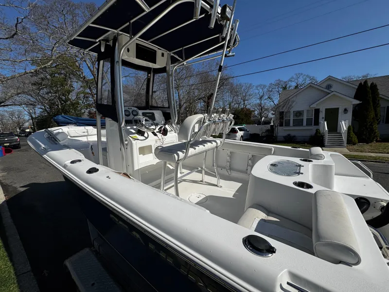 Slide: The Image of 2012 Sea Hunt Triton 210 boat with T-top and seating, parked on a residential street. - 4