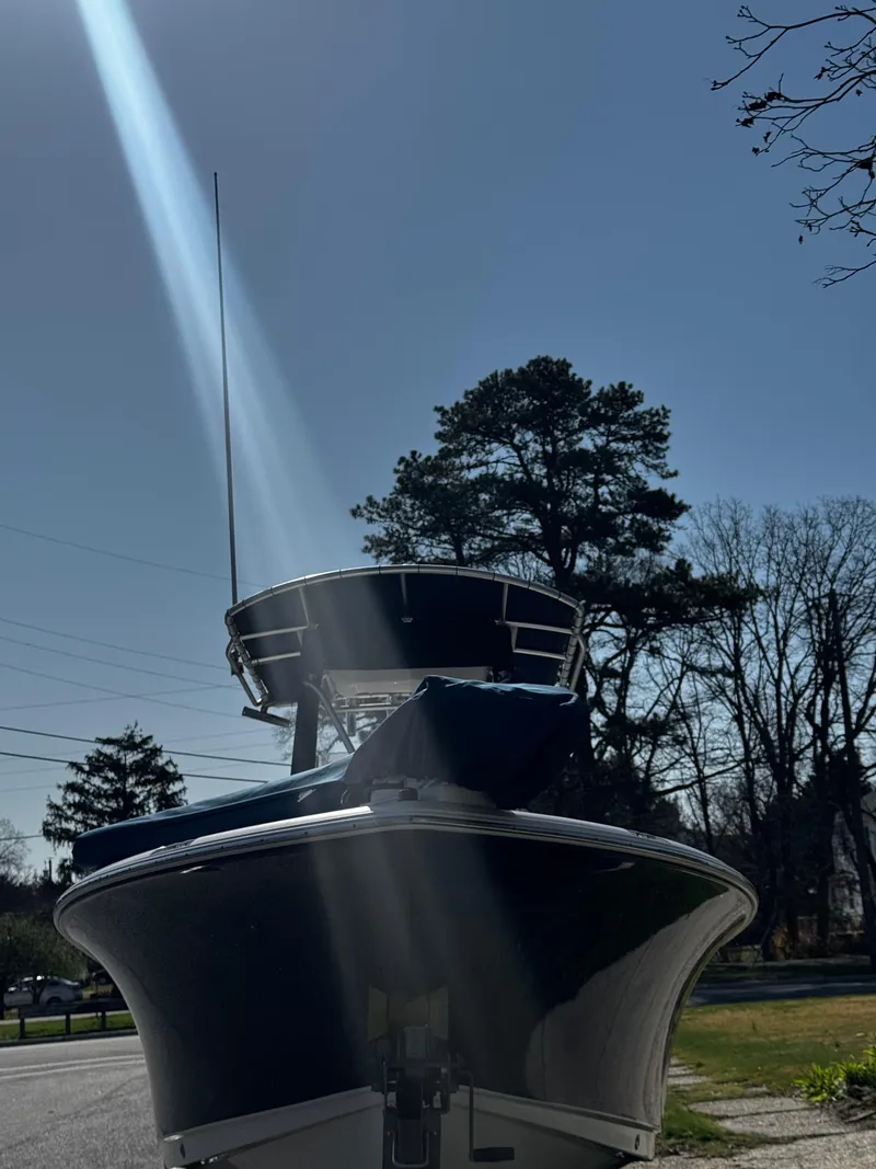 Slide: The Image of 2012 Sea Hunt Triton 210 boat under sunlight, with trees and clear sky in the background. - 6
