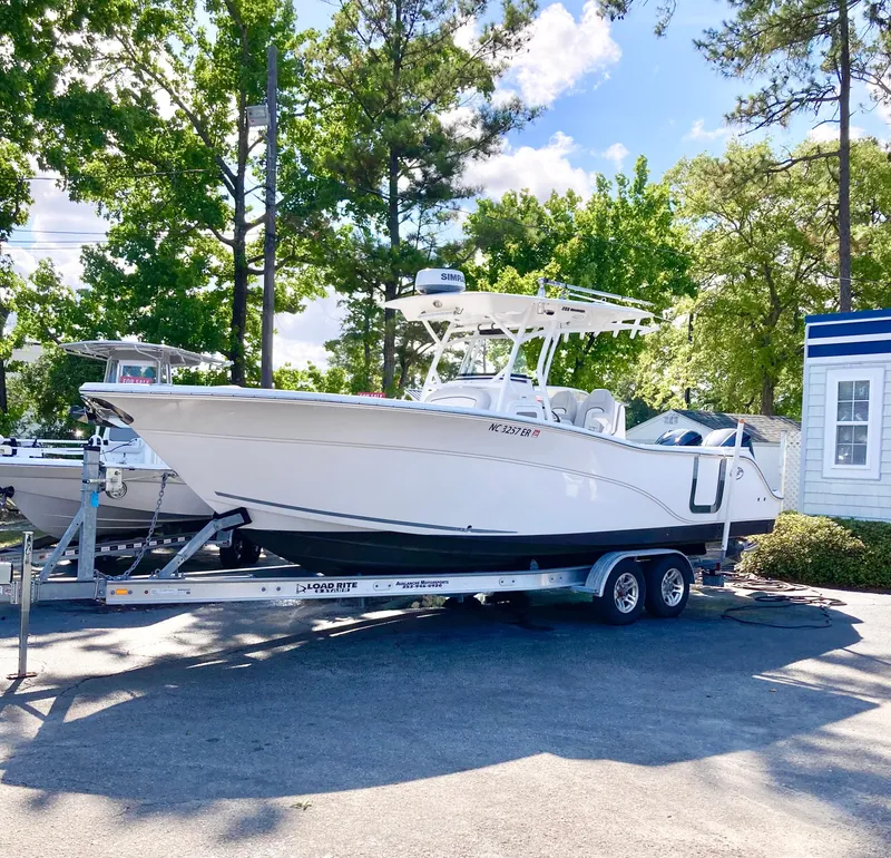 Slide: The Image of 2020 Sea Fox 288 Commander boat on trailer, parked outdoors with trees in background. - 1