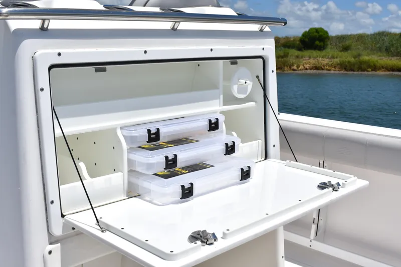 Slide: The Image of Sea Fox 288 Commander 2020 boat storage compartment with tackle boxes by the water. - 28