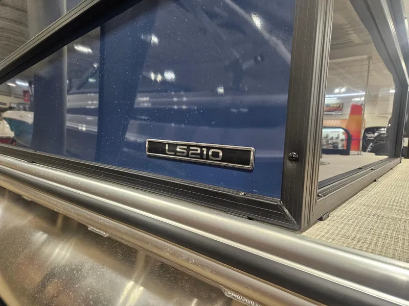 Slide: The Image of 2025 Lowe LS210 boat detail with model badge in showroom setting. - 10