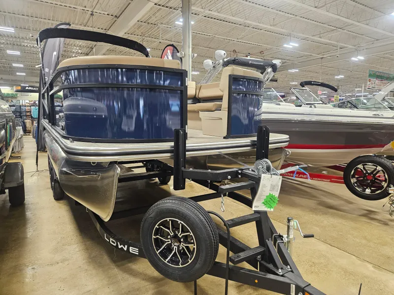 Slide: The Image of 2025 Lowe LS210 pontoon boat on display in a showroom, featuring a sleek blue design. - 2