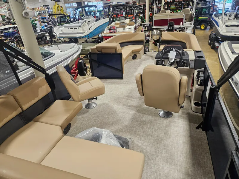Slide: The Image of 2025 Lowe LS210 pontoon boat interior with beige seating and steering console in showroom. - 3
