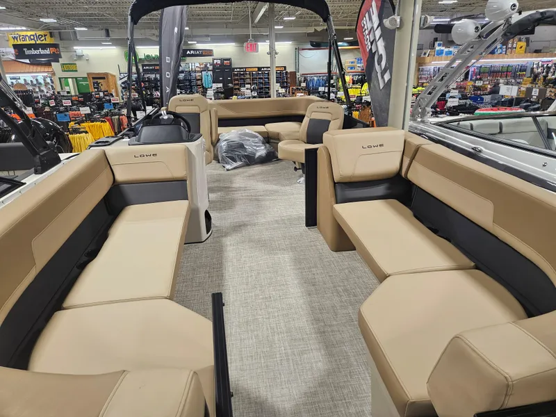 Slide: The Image of 2025 Lowe LS210 pontoon boat interior with beige seating, displayed in a showroom. - 5