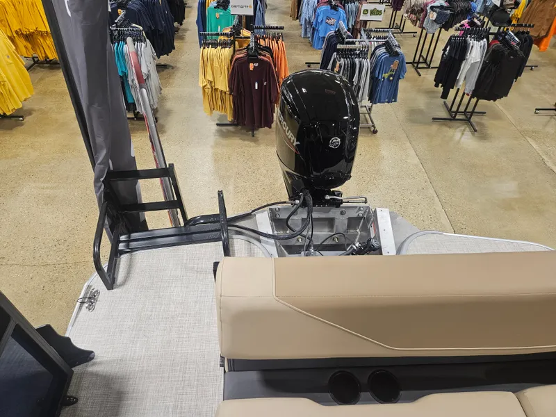 Slide: The Image of 2025 Lowe LS210 boat interior with motor, displayed in a store with clothing racks. - 7