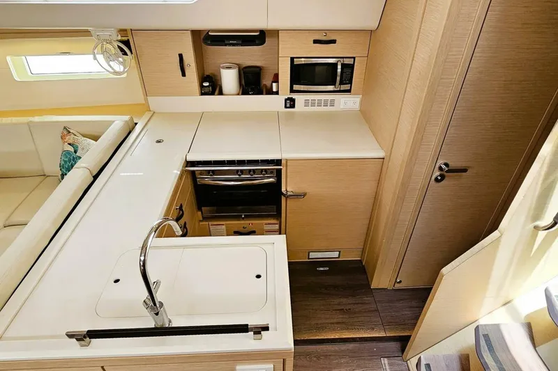 Slide: The Image of Modern kitchen interior of 2017 Jeanneau Sun Odyssey 51 yacht, featuring sleek cabinetry and appliances. - 7
