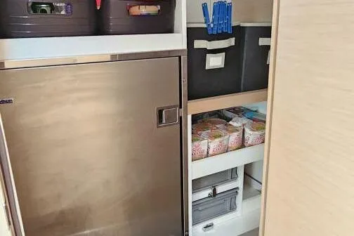 Slide: The Image of Storage area in a 2017 Jeanneau Sun Odyssey 51 yacht, featuring organized shelves and a stainless steel fridge. - 10