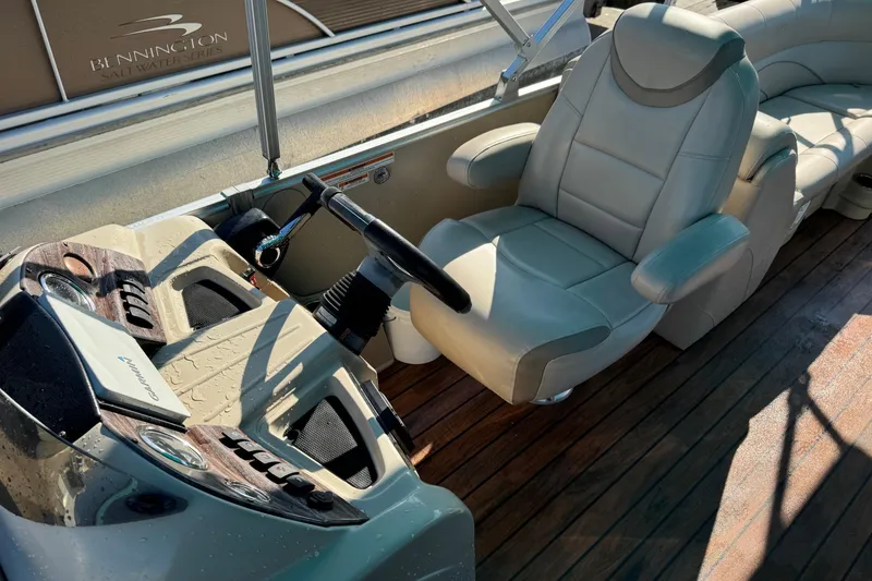 Slide: The Image of 2016 Avalon 2585 QL boat interior with steering wheel and plush seating on wooden deck. - 3