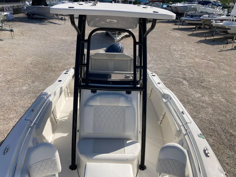 Slide: The Image of 2025 Key West 219fs boat with T-top and cushioned seating, parked on gravel. - 12