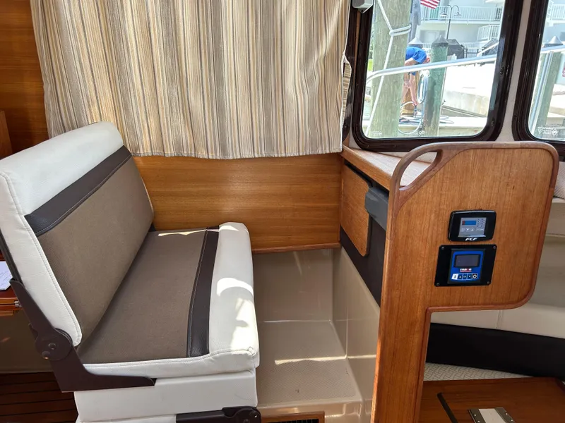 Slide: The Image of 2017 Ranger Tugs R-27 interior with cushioned seating and control panel. - 19