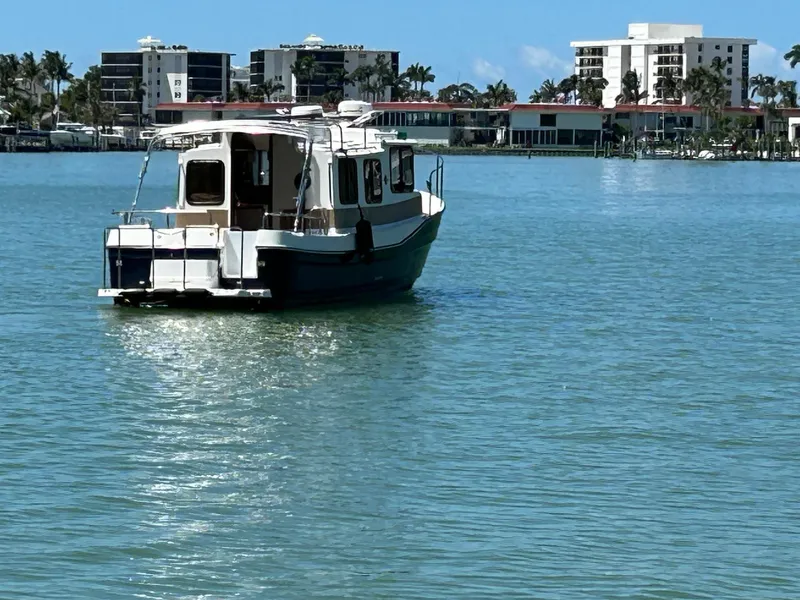 Slide: The Image of 2017 Ranger Tugs R-27 boat on calm water with buildings in the background. - 2