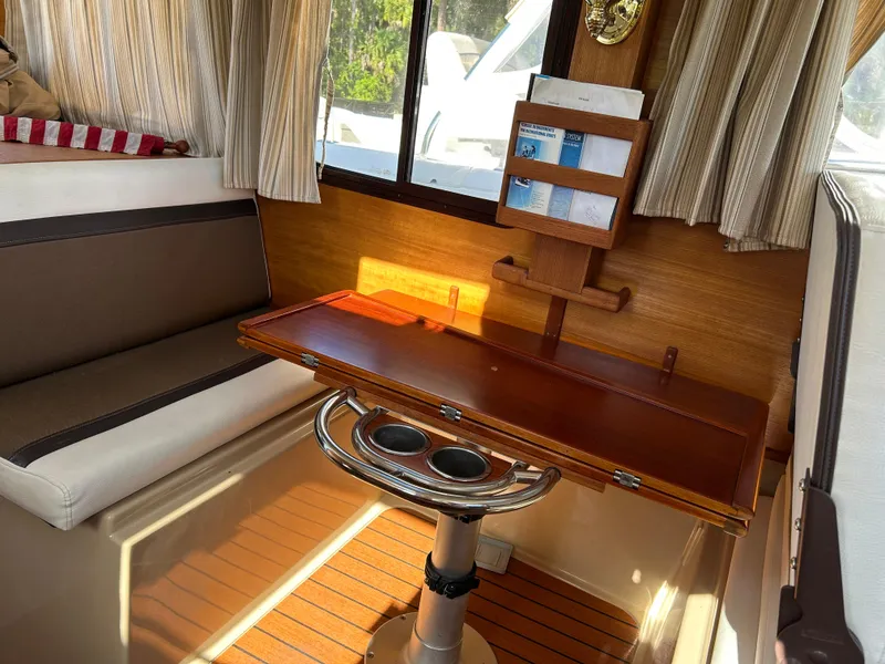 Slide: The Image of Interior of 2017 Ranger Tugs R-27 with wooden table and seating area. - 21