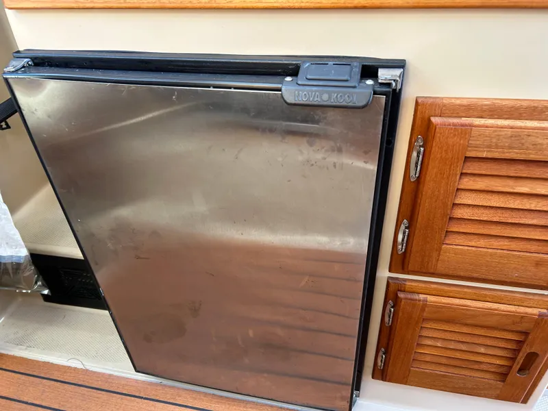 Slide: The Image of Stainless steel fridge on 2017 Ranger Tugs R-27 boat, next to wooden cabinets. - 31