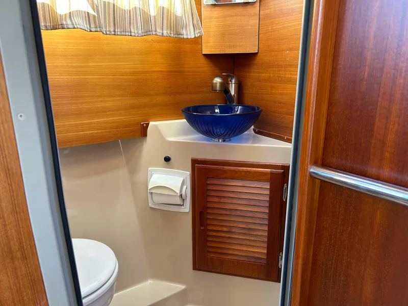 Slide: The Image of 2017 Ranger Tugs R-27 boat bathroom with wooden cabinetry and blue vessel sink. - 35