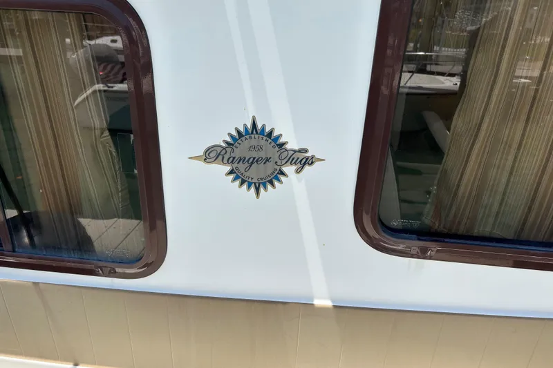 Slide: The Image of 2017 Ranger Tugs R-27 boat emblem between two windows. - 9